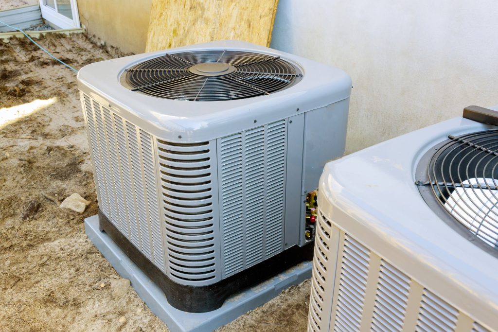 "Outdoor condenser unit of a ductless HVAC system beside a small house"